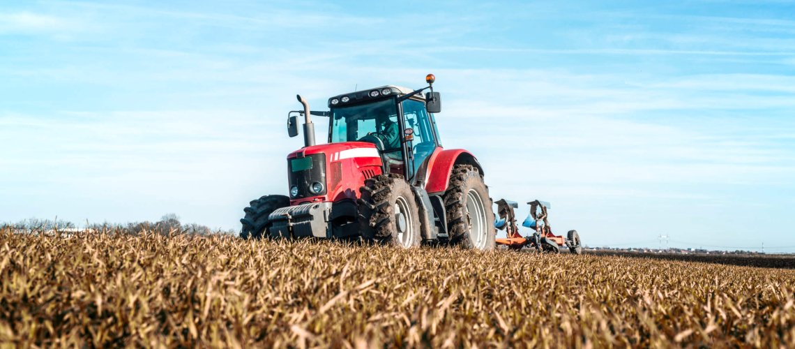 Tractor agricultural machine cultivating field.